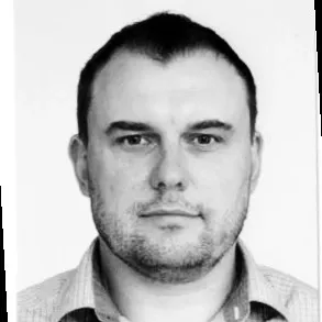 Černobílý portrét muže s krátkými vlasy a neutrálním výrazem.