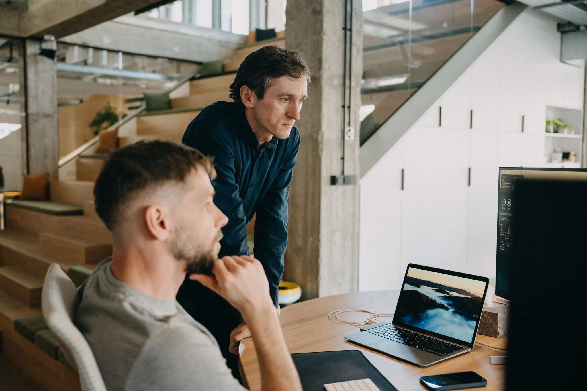 Two men collaborating and looking at a computer screen in a modern office.