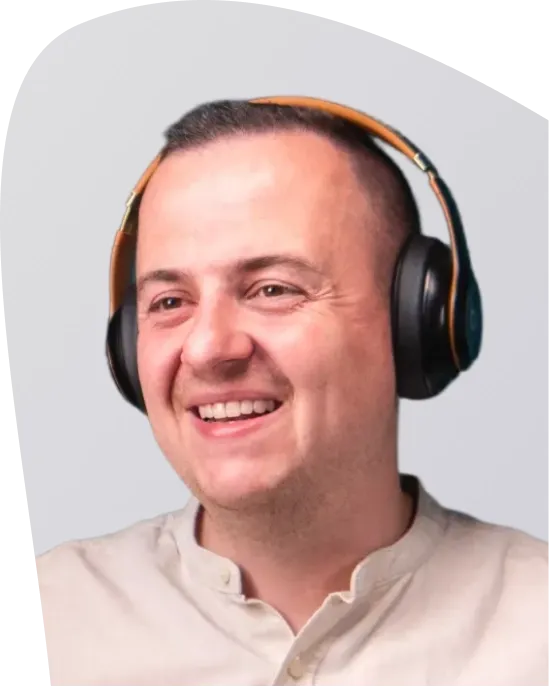 Smiling man with short hair wearing black and orange headphones.