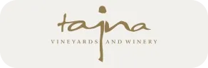 Logo Tajna Vineyards and Winery s elegantním zlatým nápisem na světlém pozadí.